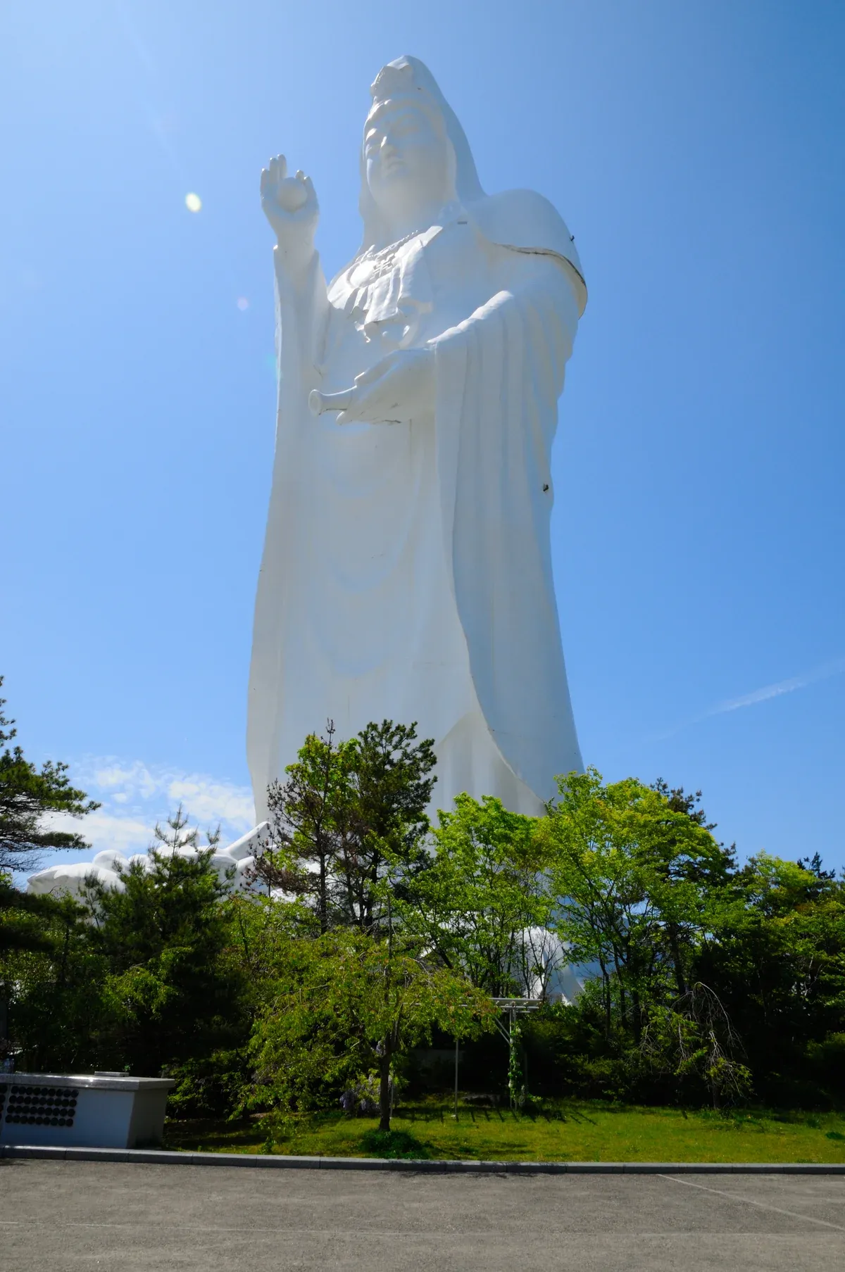 The tall white Sendai Daikannon statue rising above trees against a blue sky