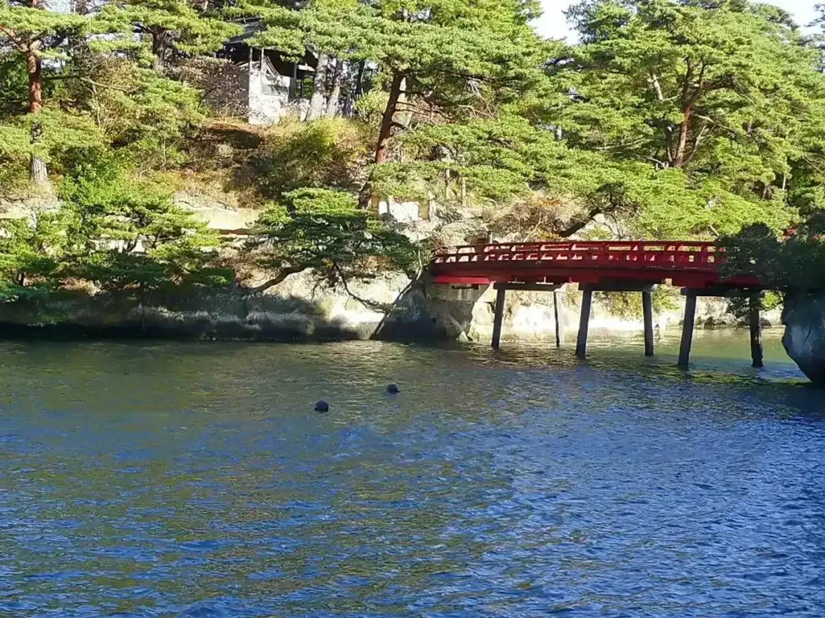 Red Togetsu Bridge crossing to Oshima island among pines and rocks